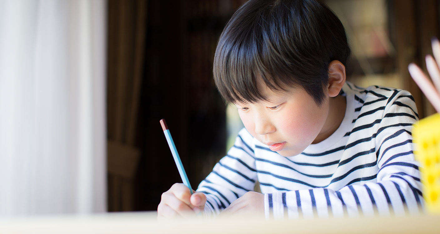 Junge schreibt mit Bleistift